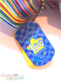 a dog tag with the number 100 on it is hanging from a colorful ribbon necklace