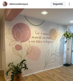 a wall with flowers painted on it in an office space, next to a plant