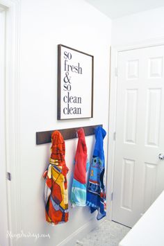 three colorful towels hanging on the wall next to a white door with a sign that says fresh and clean