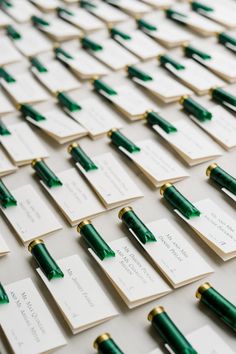 many green pens are lined up on top of each other, with name tags attached to them