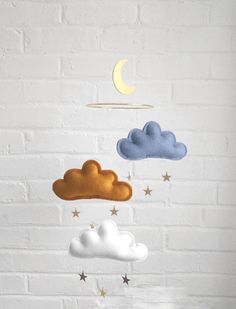 a white brick wall with three clouds and a crescent hanging from it's side