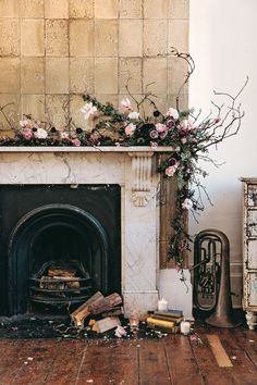 the fireplace is decorated with pink flowers and greenery on it, along with other items