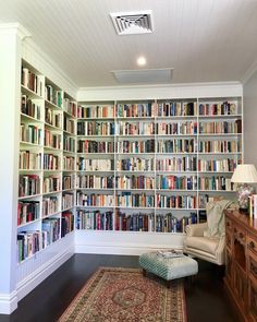 a living room filled with lots of books on top of a book shelf next to a rug