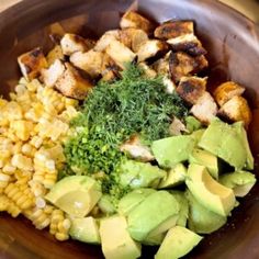 a bowl filled with corn, avocado, and chicken on top of it