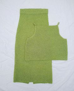 two pieces of green knitted clothing laying on top of each other