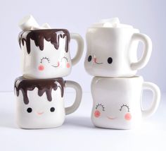 three coffee mugs with faces painted on them, one has chocolate sauce and the other has marshmallows