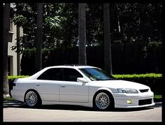 a white car parked in front of some trees