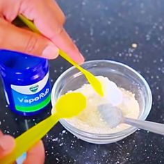 two hands holding toothbrushes over a bowl of powder