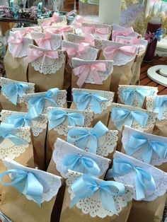 many brown bags with blue and pink bows on them are sitting next to each other