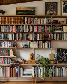 a bookshelf filled with lots of books next to a painting on the wall