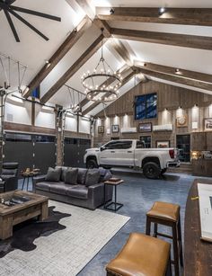 a large living room with couches, tables and two trucks in the garage area