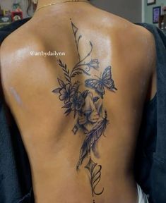 the back of a woman's tattoo with flowers and butterflies