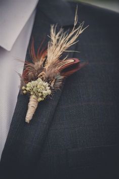 there is a boutonniere with feathers and flowers on the lapel pin