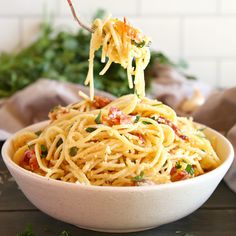 a fork full of spaghetti being lifted from a bowl