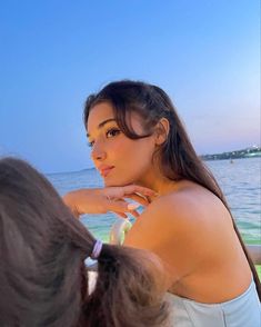 a woman standing next to the ocean with her hand on her shoulder