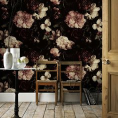 two chairs and a table in front of a floral wallpaper