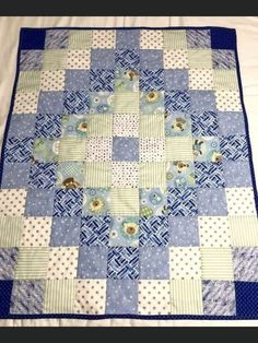 a blue and green quilt on top of a bed