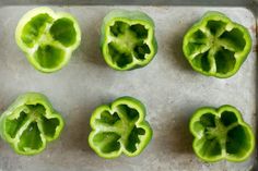 eight green peppers on a baking sheet ready to be cooked