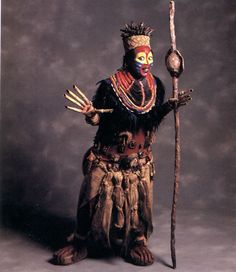 a man dressed in an elaborate costume holding a stick and wearing a headdress