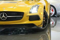 the front end of a yellow mercedes sls amg roadster car in a showroom