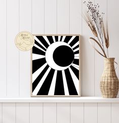 a black and white art piece on a shelf next to a vase