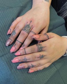 two women with matching tattoos on their hands and fingers, both holding each other's hand