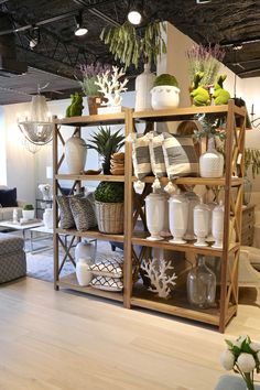 a room filled with lots of white vases and plants