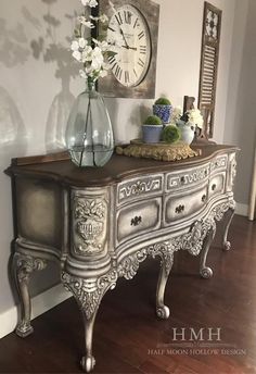 an antique dresser with flowers and a clock on the wall