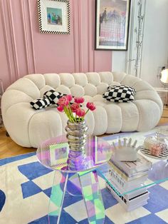 a living room filled with furniture and flowers on top of a glass table in front of a white couch