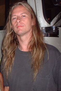 a man with long hair standing in front of a truck