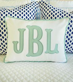 a bed with blue and white pillows that have the letter jbl on them,