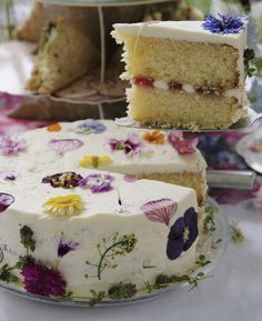 a cake with white frosting and flowers is on a plate next to other cakes