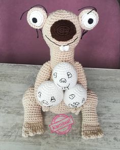 a crocheted stuffed animal sitting on top of a wooden table next to a purple wall