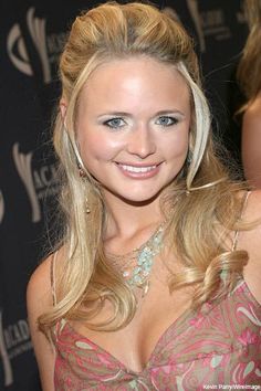 a beautiful blond woman in a pink dress posing for the camera at an awards event