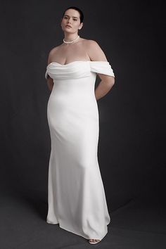 a woman in a white dress is posing for a photo with her hands on her hips