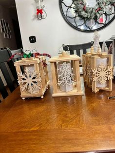 three wooden lanterns sitting on top of a table next to a christmas wreath and other decorations