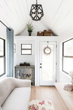 a living room filled with furniture and a white couch next to a door on top of a hard wood floor