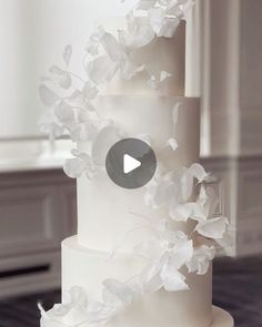 a wedding cake with white flowers on it and a video player in the middle to play