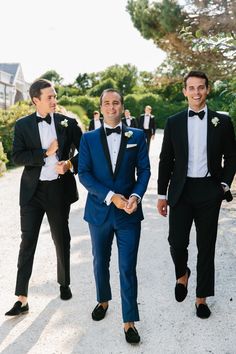 three men in tuxedos are walking down the street