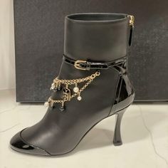 Chanel 2020 (20a Season) Lambskin Leather Ankle Booties Have A Tonal Patent Leather Cap Toe And Back And 3.25" Curved Patent Leather Heel. Patent Leather Wrap Around Belt With Goldtone Buckle. Rows Of Goldtone Chains With Multiple Charms (Camellia, Cc, Pearls, Blazer Adorn The Front. Padded Leather Insole. Leather Sole. Back Zip. Shaft: 5.5". Made In Italy. Designer Color: Black. Size: 36 Eu (Insole: 9 1/8") Typically Chanel Shoes Run Small. Brand New With The Box. Elegant Ankle-high Heeled Boots, Formal High Heel Boots With Chain Strap, Elegant Formal Boots With Chain Strap, Evening High Heel Boots With Chain Strap, Luxury Evening Ankle Strap Boots, Chanel Ankle Boots, Chanel 2020, Square Toe Ankle Boots, Sock Ankle Boots