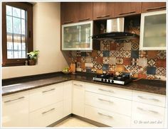 a kitchen with white cabinets and tiled backsplash, black counter tops, and wood trim