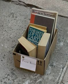 there is a cardboard box with books in it on the sidewalk next to a fire hydrant