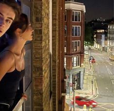 two people standing on a balcony looking out at the street