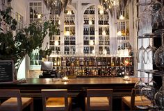 a dining room filled with lots of glassware and bottles on the wall next to a wooden table