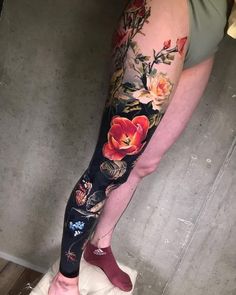 a woman's leg with flowers on it and an orange flower in the center