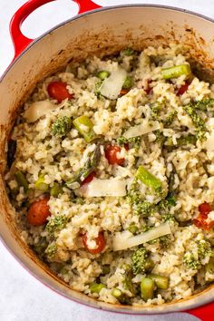 a pot filled with rice and vegetables on top of a white tablecloth next to a red spatula