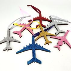 six different colored airplanes are arranged in a circle on a white surface with ribbons around them