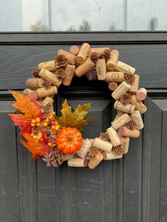 a wreath made out of wine corks and autumn leaves sits on the front door