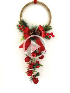 a christmas decoration hanging from the side of a wall with pine cones and red berries