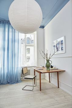 a room with a table, chairs and a large white ball hanging from the ceiling